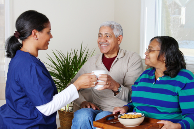 caregiver and an elder couple smiling